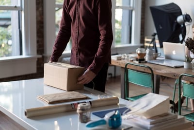 A man packing a package on a table. 