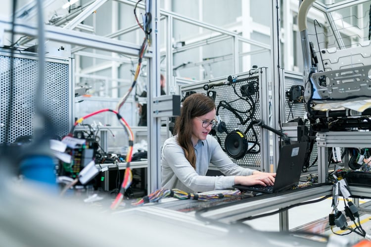 A woman working on a computer in a manufacturing plant.
