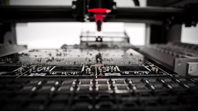 A machine is constructing a PCB.