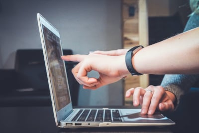 A close-up of two people working on a laptop.