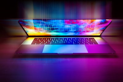 A half-open multi-colored laptop on a desk.