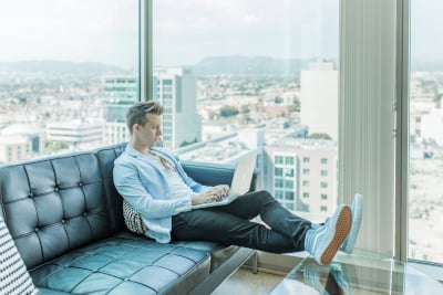 A man sitting on a sofa while using a laptop.