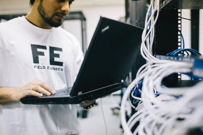 A man holding a laptop and inspecting hardware.