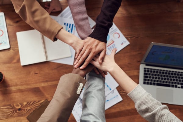 People gathering hands after creating a plan to reduce downtime during business relocations