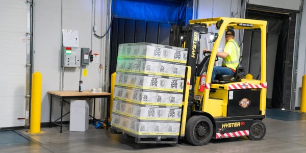 A person driving a forklift inside a warehouse.