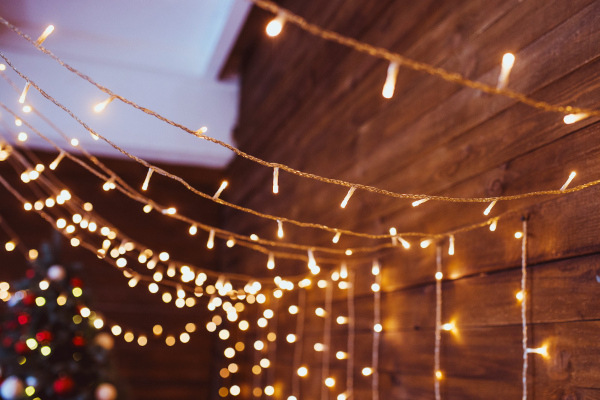 String lights handing on the wall with a Christmas tree in the background