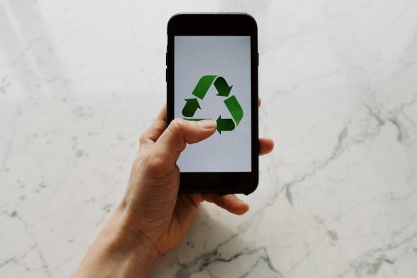 A phone with the recycle sign on the screen
