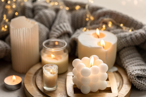 Six different shapes of candles lighting up with string light in the background