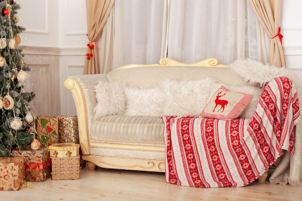 A carpet and a pillow with Christmas pattern on it placing on a white sofa