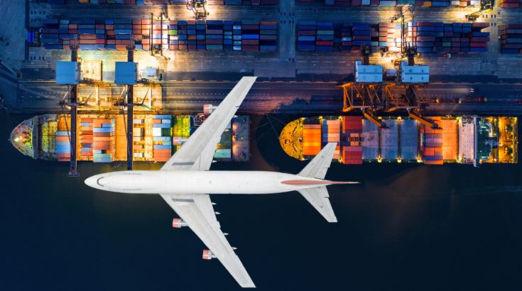 The top view of a plane flying over cargo ships