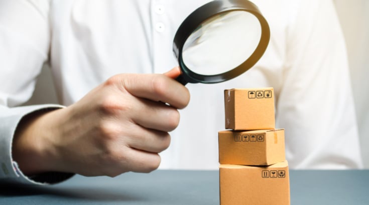 A man using a magnify glass to look at small cartons
